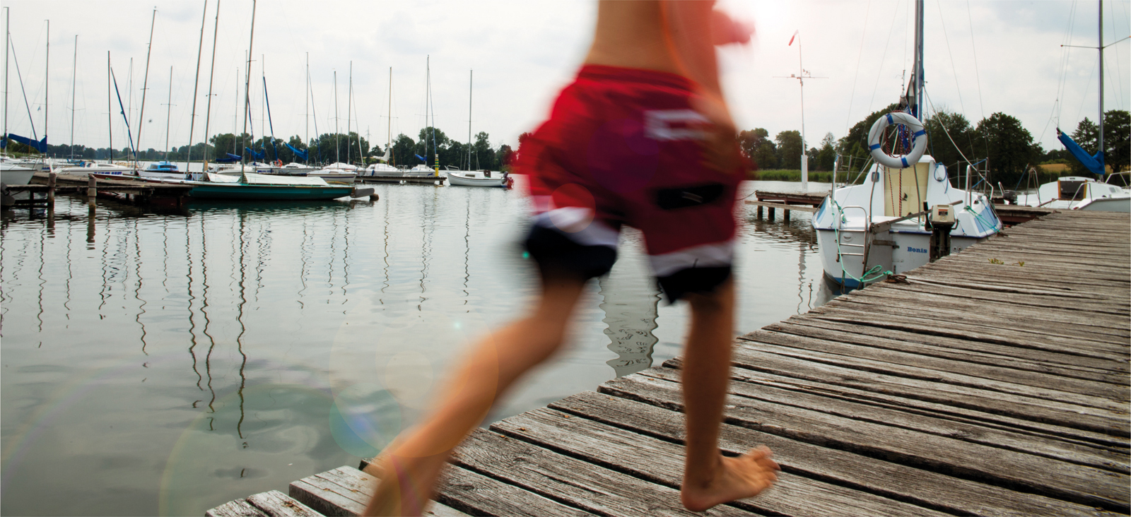 Chłopiec biegnący na pomoście Jeziora Grzymisławskiego